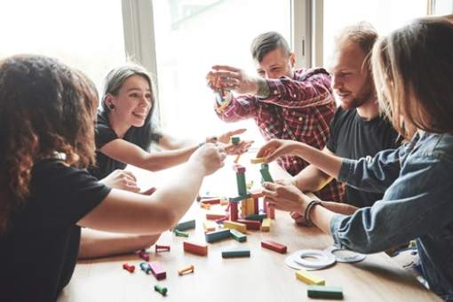 group creative friends sitting wooden table people were having fun while playing board game web